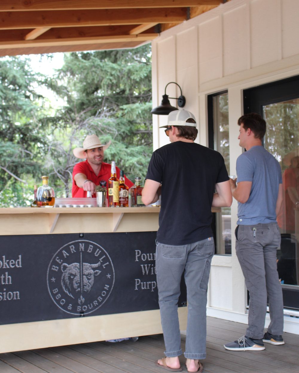 Bear n Bull bartender pouring drinks behind the branded wooden bar at a private event.